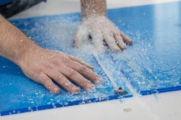 Hände auf einer blauen Platte mit Sägespänen